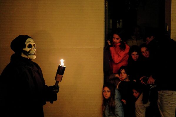 Turistas y residentes locales observan a un penitente vestido con un traje de esqueleto que interpreta la danza de la muerte con un objeto que simboliza el paso del tiempo y la muerte, durante la procesión pascual en Verges, Cataluña, España. - Sputnik Mundo