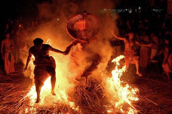 Un intérprete vestido como una deidad hindú salta a través del fuego como parte de un ritual durante el festival Theyyam, también conocido como Kaliyattam, Kérala, la India. - Sputnik Mundo