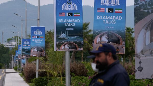 Personal de seguridad se encuentra junto a carteles relacionados con las negociaciones entre Estados Unidos e Irán, a las afueras de un centro de atención a los medios de comunicación en Islamabad, Pakistán, el 11 de abril de 2026  - Sputnik Mundo