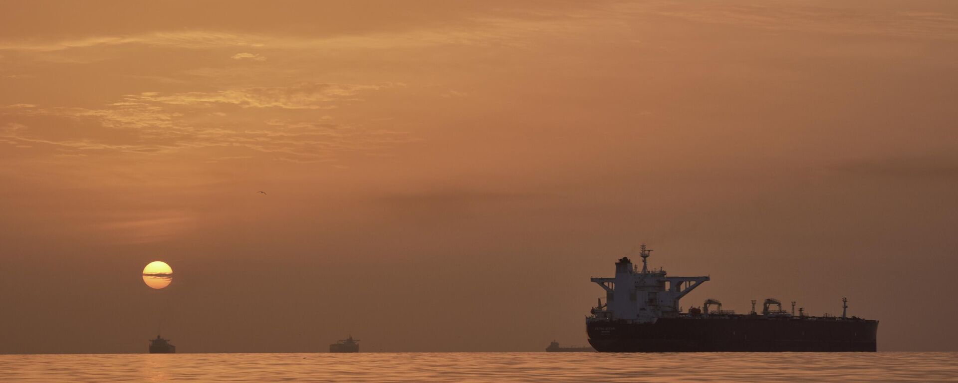 El sol sale tras los buques cisterna anclados en el estrecho de Ormuz - Sputnik Mundo, 1920, 19.04.2026