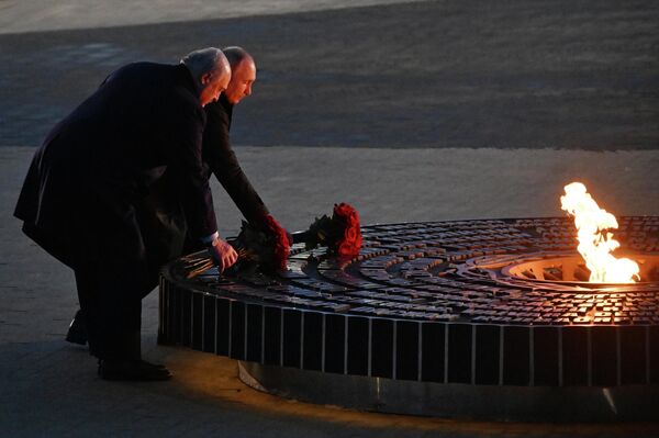 El presidente ruso, Vladímir Putin, y el presidente bielorruso, Alexander Lukashenko, depositan flores en la Llama Eterna durante la ceremonia de inauguración de un monumento conmemorativo a los civiles soviéticos que fueron víctimas del genocidio nazi durante la Gran Guerra Patria en la aldea de Záitsevo, región rusa de Leningrado. - Sputnik Mundo