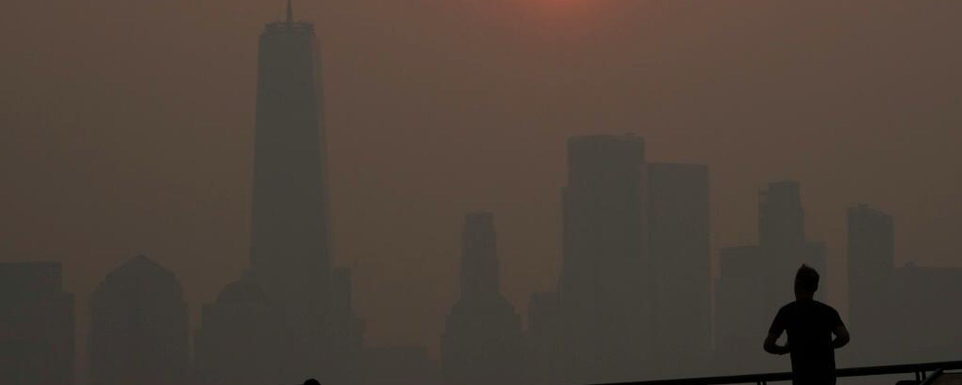 Un hombre corre frente al amanecer sobre el horizonte del bajo Manhattan en Jersey City, Nueva Jersey, en medio del denso humo proveniente de los incendios forestales canadienses (archivo) - Sputnik Mundo, 1920, 23.04.2026