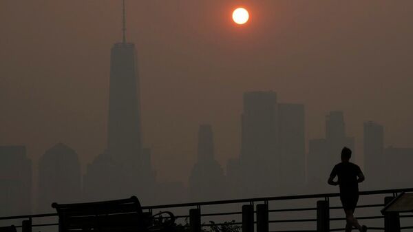 Un hombre corre frente al amanecer sobre el horizonte del bajo Manhattan en Jersey City, Nueva Jersey, en medio del denso humo proveniente de los incendios forestales canadienses (archivo) - Sputnik Mundo