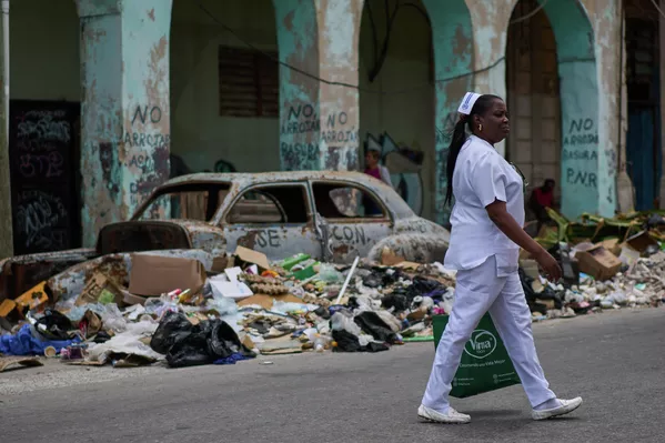 Una enfermera camina junto a la basura y un auto clásico abandonado en una calle de La Habana, Cuba. - Sputnik Mundo