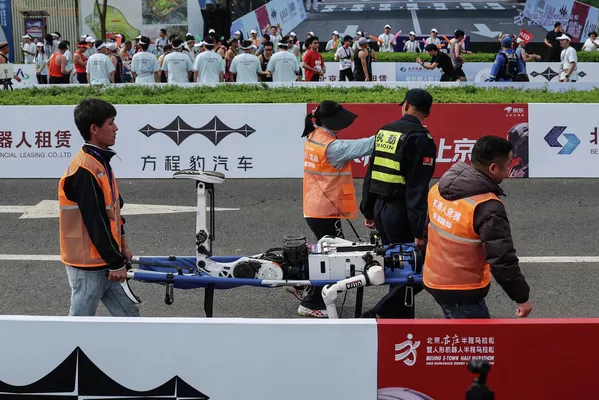 Personal transporta un robot humanoide que se estrelló tras cruzar la meta del segundo medio maratón de robots humanoides en Pekín, China. - Sputnik Mundo