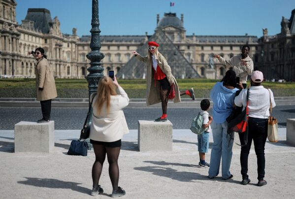 Turistas posan para una foto frente a la pirámide de cristal del Museo del Louvre en un soleado día de primavera en París, Francia. - Sputnik Mundo