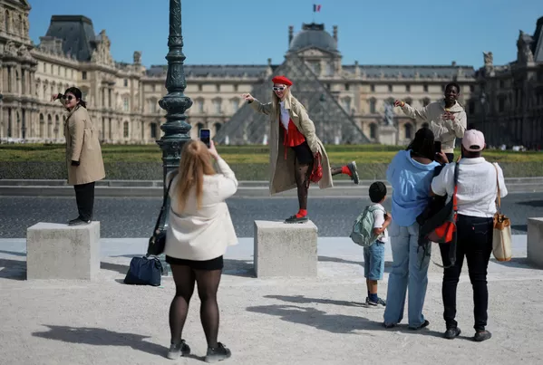 Turistas posan para una foto frente a la pirámide de cristal del Museo del Louvre en un soleado día de primavera en París, Francia. - Sputnik Mundo