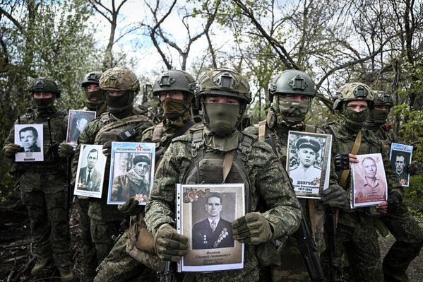 Soldados rusos en la zona de la operación militar especial en Ucrania posan con retratos de sus ancestros en el marco de la campaña El Regimiento Inmortal, dedicada al Día de la Victoria en la Segunda Guerra Mundial. - Sputnik Mundo