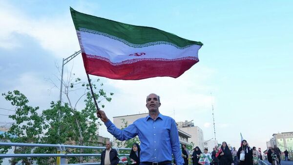 Un hombre sostiene una bandera iraní en una manifestación en Teherán, Irán, el 29 de abril de 2026 - Sputnik Mundo