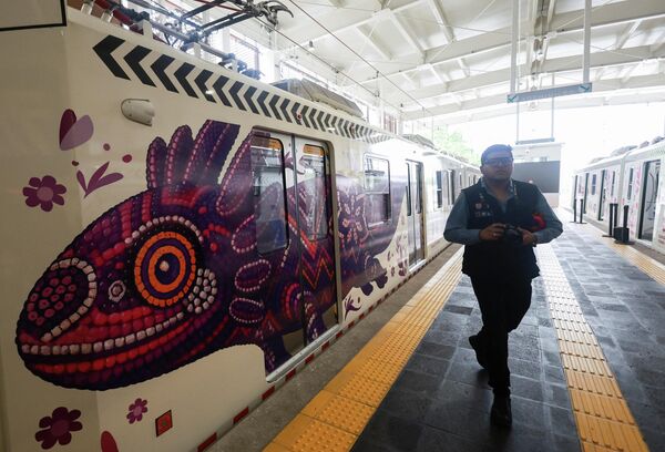 El animal también se ve en los trenes modernos, que se pusieron en marcha en la remodelación del tren ligero, llamado El Ajolote, como parte de la infraestructura de movilidad rumbo al mundial.En la foto: un hombre pasa junto a un cuadro de un ajolote en un vagón de tren durante la inauguración de la línea de tren ligero modernizada. - Sputnik Mundo