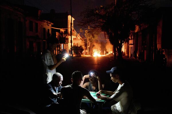 Un grupo de cubanos juega una partida de dominó iluminándola con sus teléfonos móviles, debido a los prolongados cortes de electricidad causados por el bloqueo energético impuesto por EEUU. - Sputnik Mundo