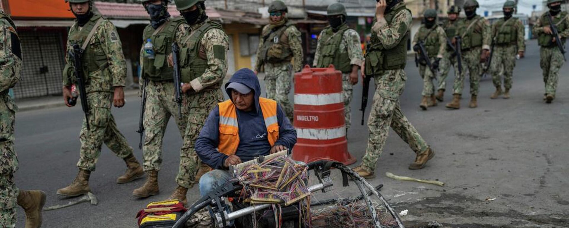 Un trabajador repara cables mientras soldados patrullan Durán, ciudad hermana de Guayaquil, Ecuador. - Sputnik Mundo, 1920, 19.05.2026