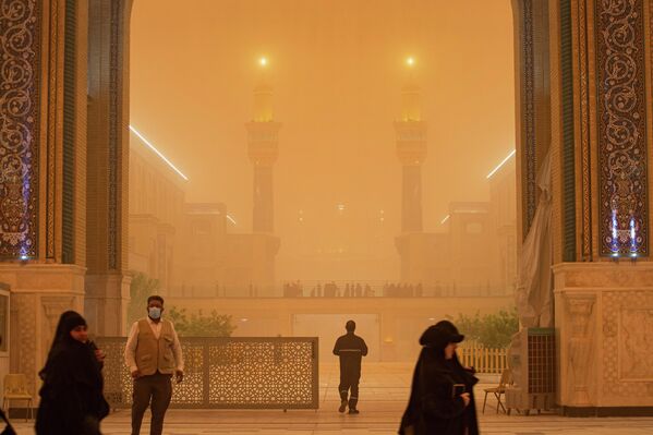 Personas caminan cerca del santuario del imán Alí durante una fuerte tormenta de arena en Náyaf, Irak. - Sputnik Mundo