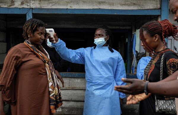 Un profesional médico mide la temperatura de una mujer que pasa por un puesto de control durante el nuevo brote de ébola en la República Democrática del Congo. - Sputnik Mundo