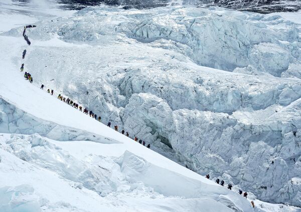 Los escaladores avanzan en una larga fila mientras se dirigen a la cima del Everest. - Sputnik Mundo