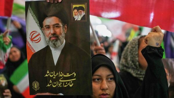 Una mujer sostiene un retrato del líder supremo de Irán, el ayatolá Mojtabá Jameneí. - Sputnik Mundo