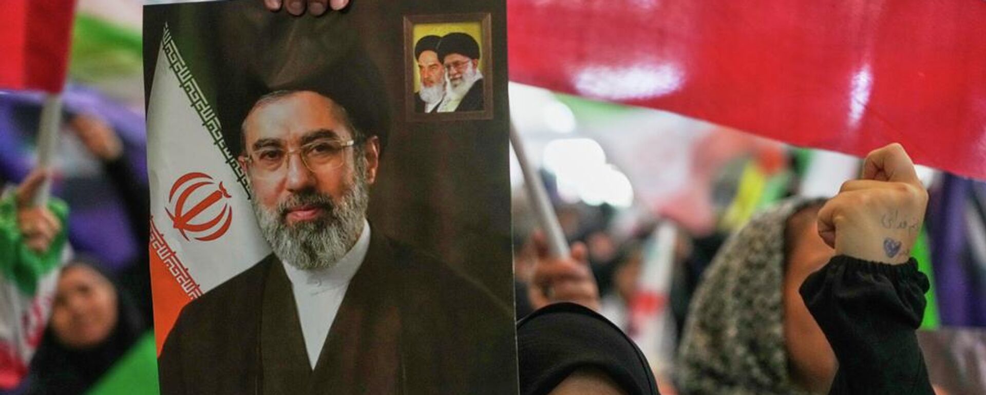 Una mujer sostiene un retrato del líder supremo de Irán, el ayatolá Mojtabá Jameneí - Sputnik Mundo, 1920, 13.06.2026
