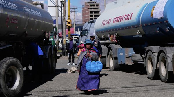Una mujer pasa junto a unos camiones cisterna que bloquean una carretera durante una huelga provocada por la escasez de gasóleo en El Alto, Bolivia - Sputnik Mundo