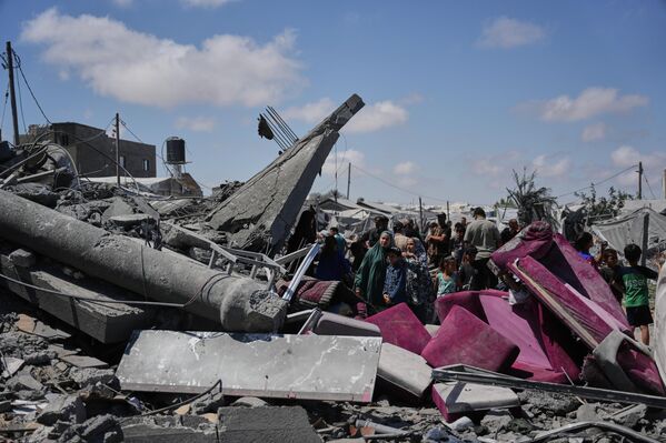 Unos palestinos inspeccionan los escombros de un edificio destruido en un ataque aéreo israelí en la ciudad de Jan Yunis, en el sur de la Franja de Gaza. - Sputnik Mundo