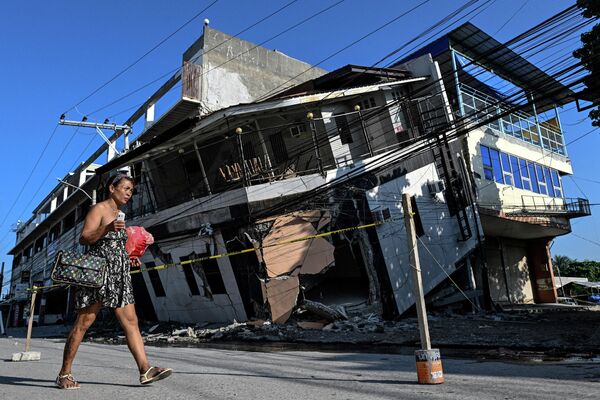 Una mujer pasa junto a un edificio derrumbado tras el terremoto de magnitud 7,8, en la ciudad de General Santos, al sur de Filipinas. - Sputnik Mundo