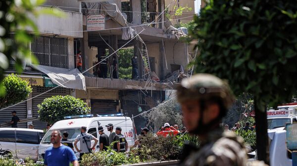 Un oficial del Ejército libanés se para mientras oficiales de Policía y personal de emergencia trabajan en el lugar de un ataque israelí en los suburbios del sur de Beirut, Líbano, 14 de junio de 2026 - Sputnik Mundo