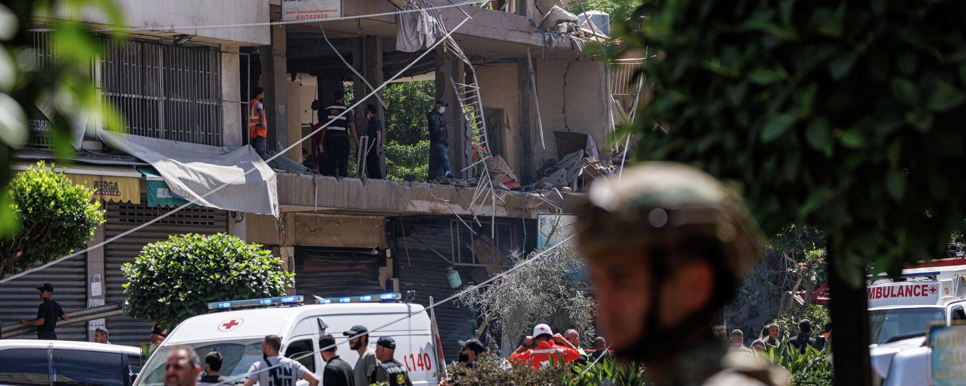 Un oficial del Ejército libanés se para mientras oficiales de Policía y personal de emergencia trabajan en el lugar de un ataque israelí en los suburbios del sur de Beirut, Líbano, 14 de junio de 2026 - Sputnik Mundo, 1920, 14.06.2026