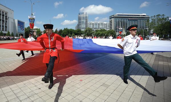 Cosacos del Kubán y alumnos del puesto Nº1 de la ciudad de Krasnodar asisten a la ceremonia solemne de izamiento de la bandera estatal con motivo del Día de Rusia. - Sputnik Mundo