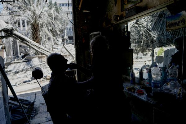 Un peluquero libanés atiende a un cliente en su salón, dañado por los bombardeos israelíes. - Sputnik Mundo