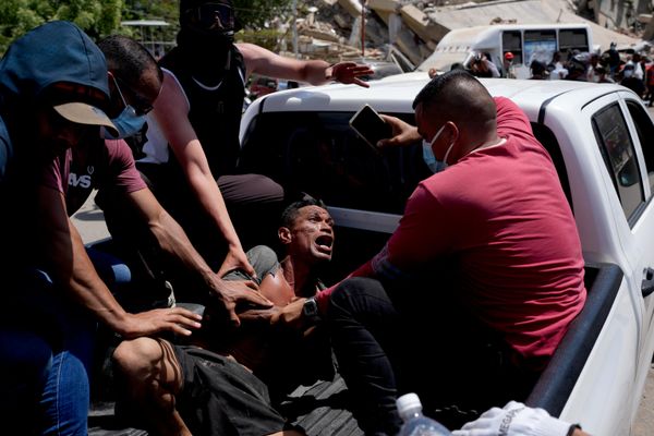 Unos vecinos transportan a un hombre rescatado de entre los escombros tres días después de los terremotos en La Guaira. - Sputnik Mundo