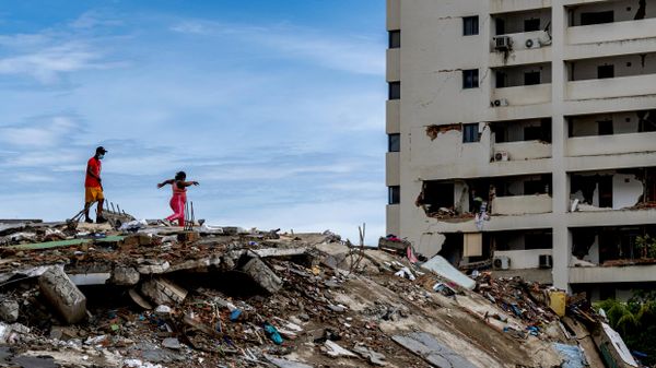 Habitantes locales caminan sobre los escombros de un edificio derrumbado en Caraballeda, estado de La Guaira, Venezuela, el 30 de junio de 2026, tras los dos terremotos del 24 de junio  - Sputnik Mundo