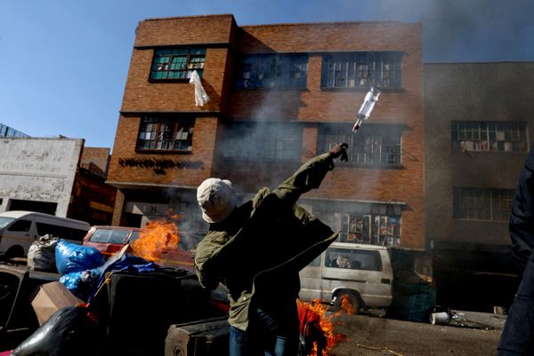 Un manifestante lanza una botella contra un edificio durante una protesta contra la inmigración en Johannesburgo, Sudáfrica. - Sputnik Mundo