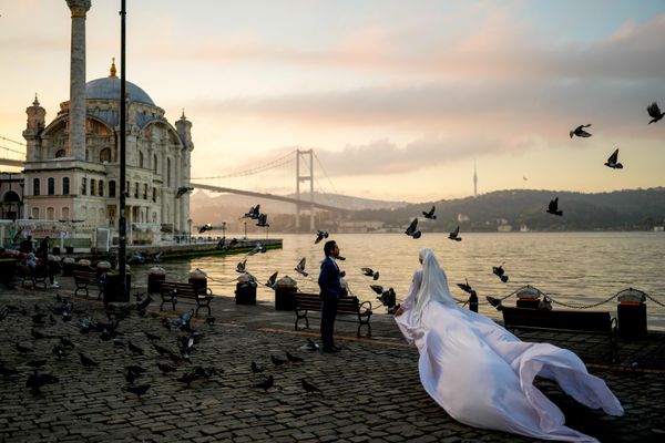 Una pareja vestida de boda posa durante una sesión fotográfica en el paseo marítimo de Ortakoy, en Estambul. - Sputnik Mundo