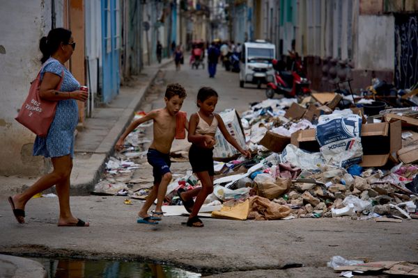 Unos niños pasan corriendo junto a un montón de basura acumulada en la calle durante un apagón en La Habana. - Sputnik Mundo
