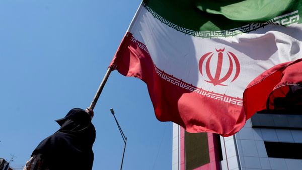 Una mujer sostiene una bandera iraní - Sputnik Mundo