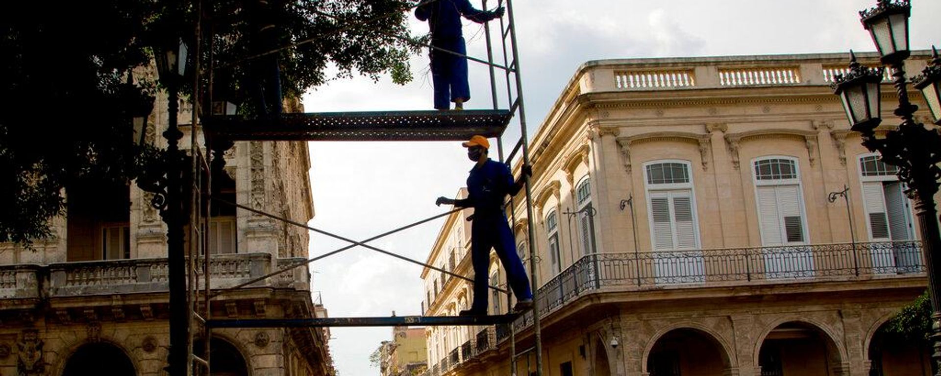 Trabajadores de la empresa privada Watt Electric construyen andamios para reparar el alumbrado público a lo largo del Paseo del Prado en La Habana, Cuba. - Sputnik Mundo, 1920, 21.07.2026
