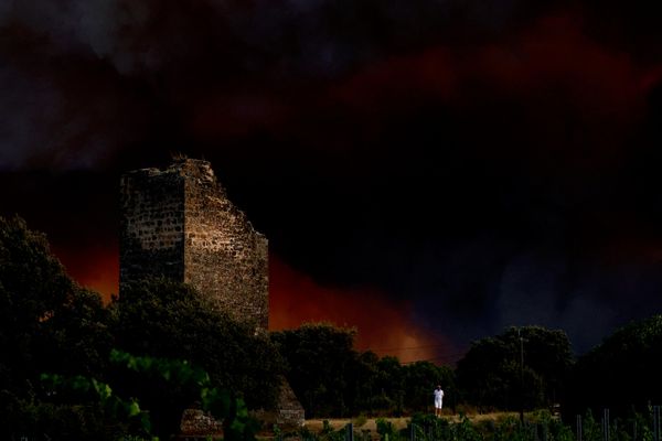 Un hombre se encuentra junto a unas ruinas mientras el humo se extiende cerca, en el pueblo de Cotignac, Francia, tras un incendio forestal devastador. - Sputnik Mundo