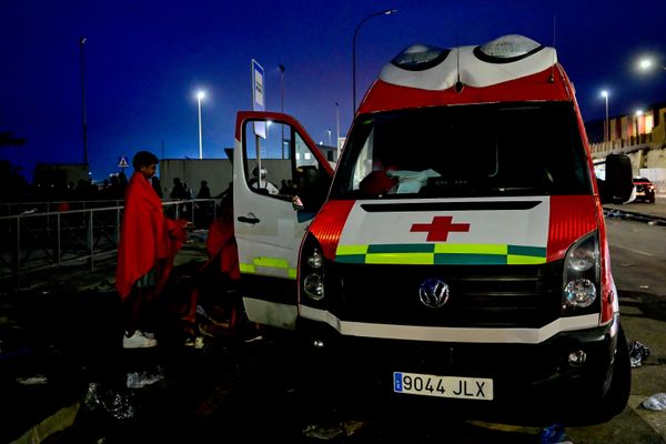 Varios migrantes marroquíes permanecen junto a una ambulancia después de llegar a España en la frontera del enclave español de Ceuta y Marruecos. - Sputnik Mundo