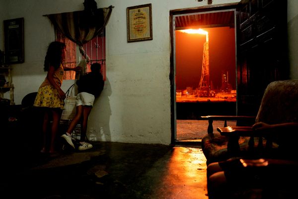 Niños miran a través de una ventana cómo arde una antorcha de gas en la Refinería Cardón, Venezuela. - Sputnik Mundo