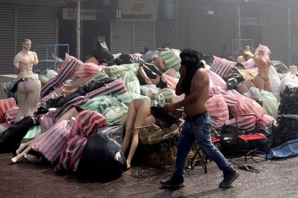 Un hombre se cubre el rostro del humo mientras pasa junto a mercancías recuperadas del mercado Feria Barrio Lindo, después de que este se incendiara durante la noche, en Santa Cruz, Bolivia. - Sputnik Mundo