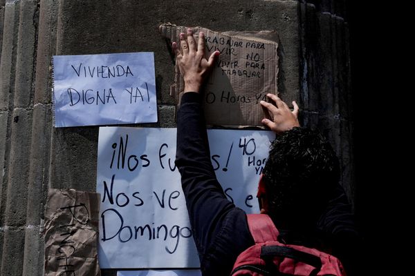 Un manifestante cuelga carteles contra la gentrificación frente a la sede del gobierno de la Ciudad de México, durante una conferencia de prensa de la jefa de Gobierno, Clara Brugada, sobre la regulación de los precios de alquiler de viviendas, el miércoles 16 de julio de 2025. (Foto AP/Marco Ugarte) - Sputnik Mundo