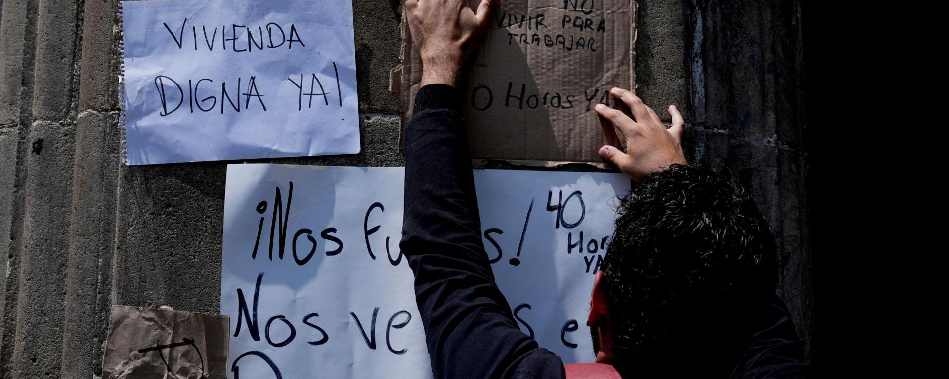 Un manifestante cuelga carteles contra la gentrificación frente a la sede del gobierno de la Ciudad de México, durante una conferencia de prensa de la jefa de Gobierno, Clara Brugada, sobre la regulación de los precios de alquiler de viviendas, el miércoles 16 de julio de 2025. (Foto AP/Marco Ugarte) - Sputnik Mundo, 1920, 18.08.2026