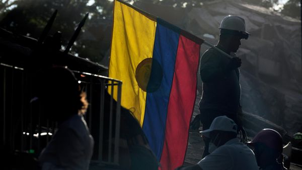 Un bombero que participa en las labores de rescate sostiene una bandera de Colombia entre los escombros, tres días después del terremoto - Sputnik Mundo