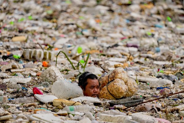 Un trabajador utiliza flotadores improvisados mientras intenta retirar un mar de basura y escombros arrastrados por las intensas lluvias monzónicas en el canal de Redemptoristas, en la ciudad de Parañaque, Filipinas. - Sputnik Mundo