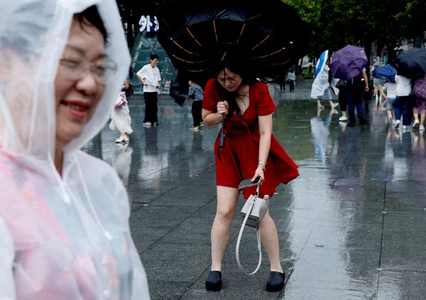 Una mujer sostiene un paraguas dado la vuelta mientras los vientos se intensifican ante la llegada del tifón Dolphin a Shanghái, China. - Sputnik Mundo