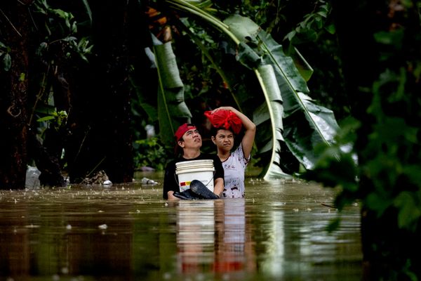 Personas llevando sus pertenencias atraviesan a pie una aldea inundada en medio de las lluvias del monzón, en la ciudad Quezon, Filipinas. - Sputnik Mundo