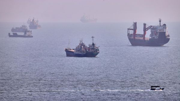 Un pequeño bote navega junto a cargueros y otros buques comerciales anclados en el estrecho de Ormuz - Sputnik Mundo