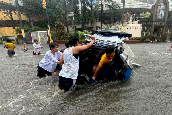 Los residentes de la ciudad filipina de Mandaluyong empujan una bicicleta por una calle anegada tras las fuertes lluvias monzónicas. - Sputnik Mundo