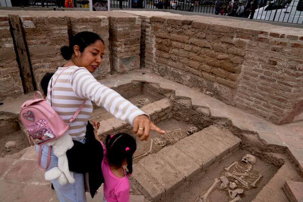 Una mujer con sus niños observa restos óseos del siglo XVI hallados durante los trabajos arqueológicos en el santuario de Santa Rosa de Lima, en Perú. - Sputnik Mundo
