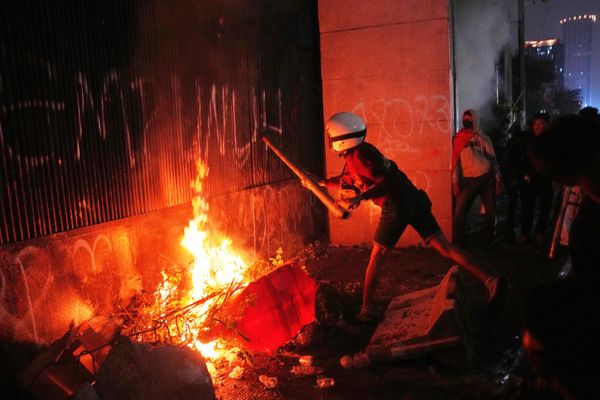 Un manifestante golpea las puertas en llamas del Parlamento indonesio en Yakarta durante una protesta para exigir un endurecimiento de la política anticorrupción. - Sputnik Mundo