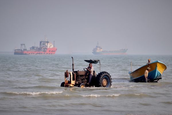 Un tractor remolca una lancha desde el mar mientras varios buques comerciales permanecen en el estrecho de Ormuz, frente a Bandar Abás, Irán. - Sputnik Mundo